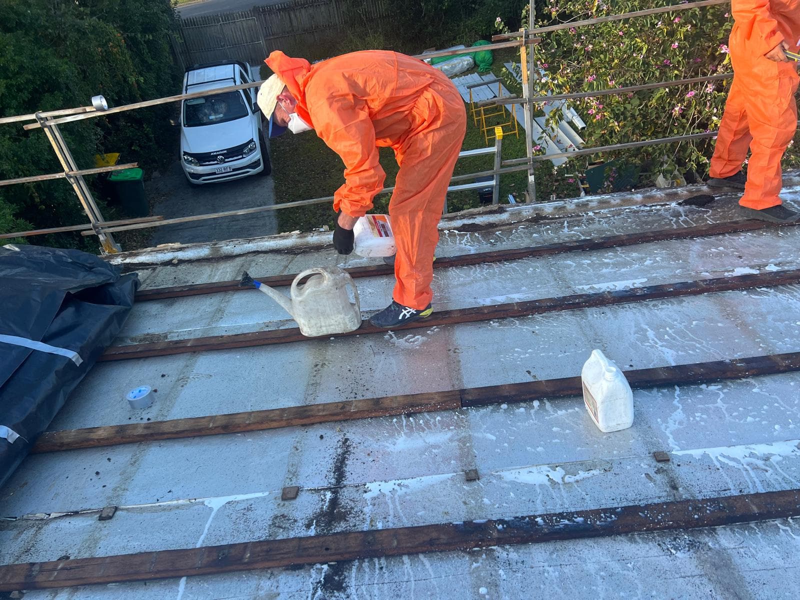 Licensed asbestos roof removal in progress in The Gap, Brisbane, with the crew in protective suits wetting down the sheets