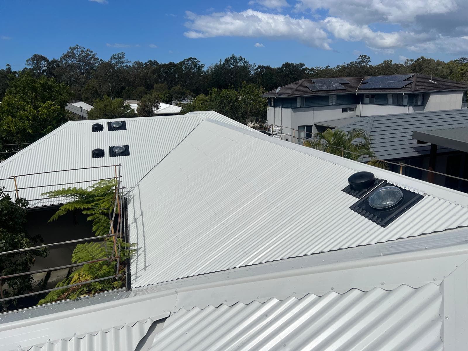 Completed light-coloured Colorbond metal roof with whirlybird ventilators and tubular skylights in Wakerley, Brisbane